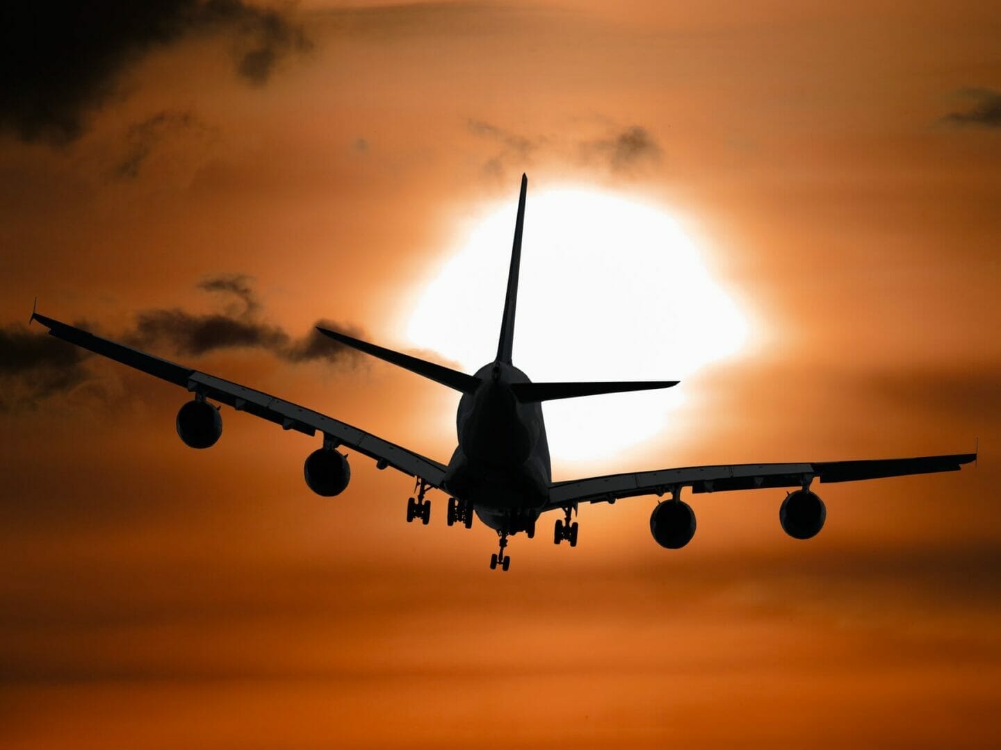Schattenbild eines Flugzeugs, das bei Sonnenuntergang fliegt – Buchen Sie günstige Flüge für Europa 