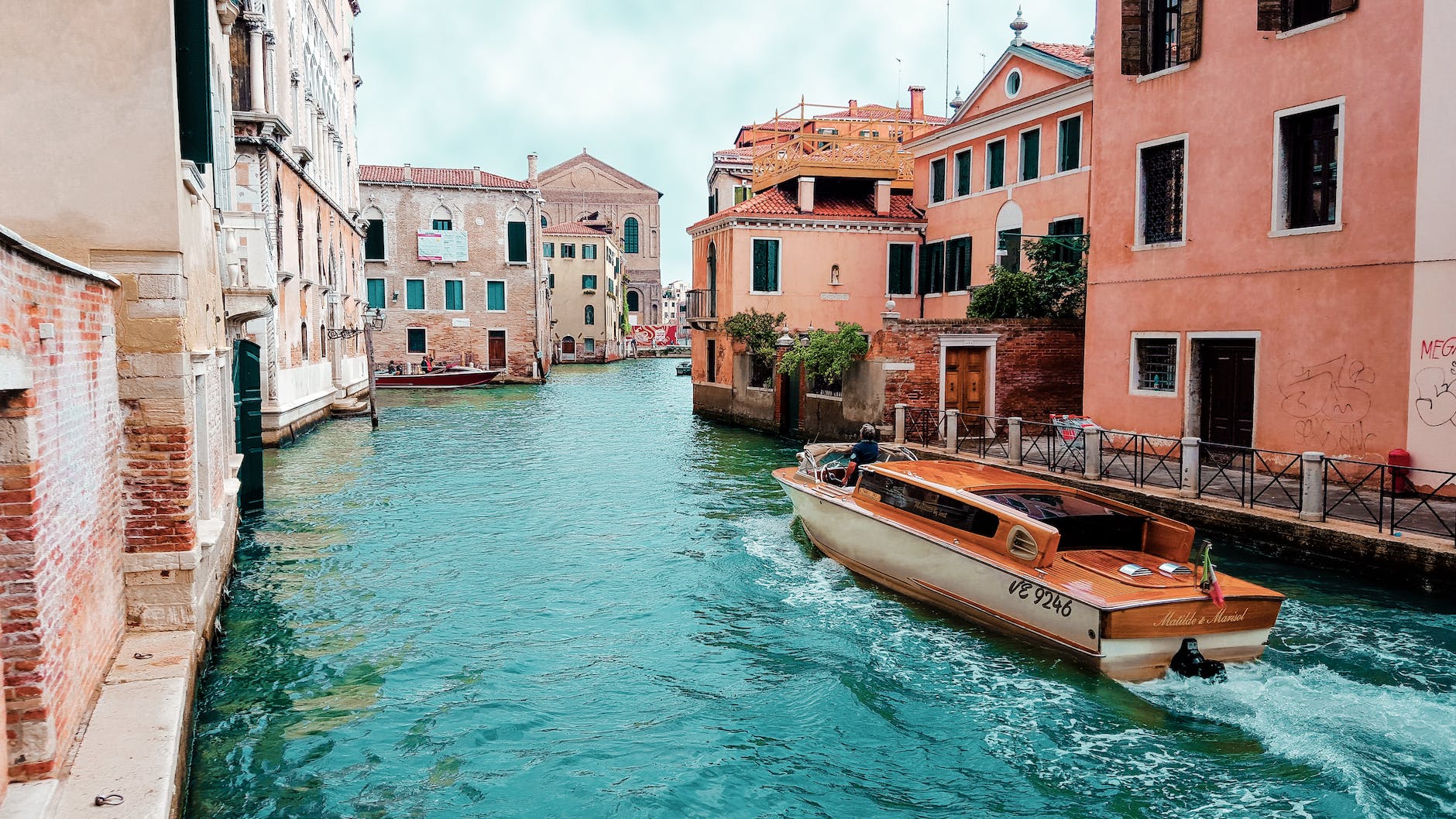 orange powerboat between medium rise buildings - Best Place in Europe to visit in February