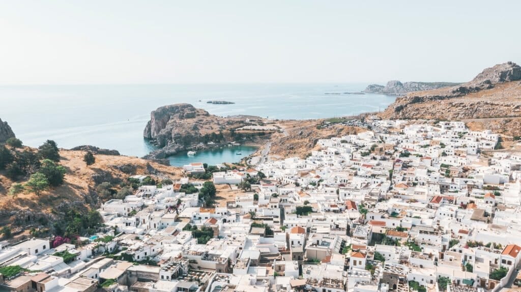 white concrete houses near body of water during daytime - Family Trip to Europe on a Budget