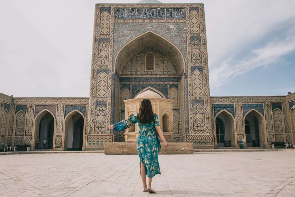 woman in teal dress standing on brown brick floor