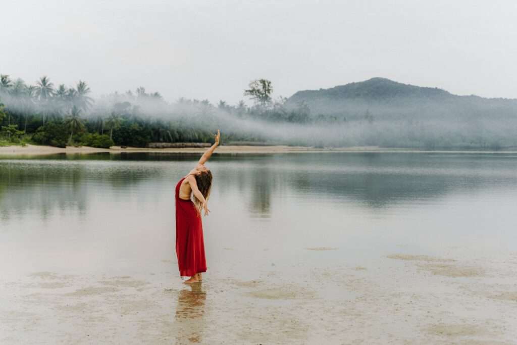 a woman in a red dress standing in the water - Tips for Solo Female Travellers