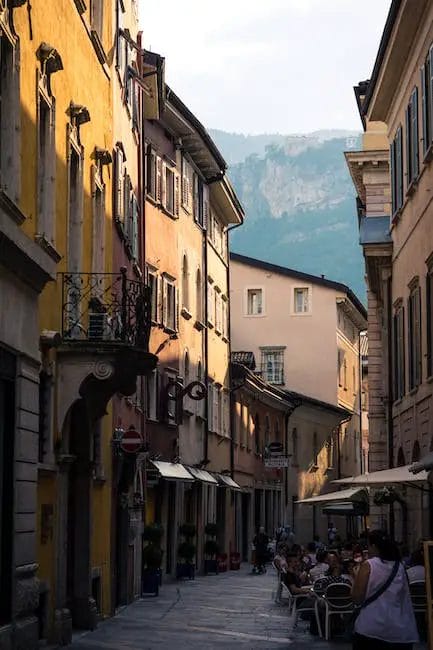 A narrow street in a city with mountains in the background.