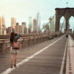 A woman is standing on the brooklyn bridge.