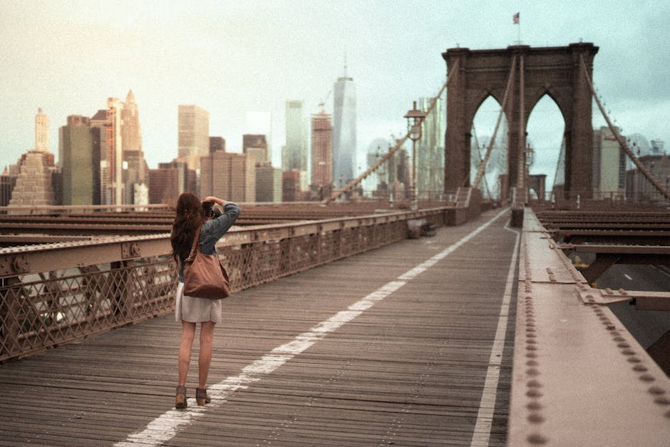A woman is standing on the brooklyn bridge.