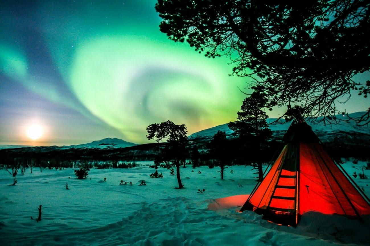 orange tent on snow covered ground during night time - Best Places to Visit in Europe in December