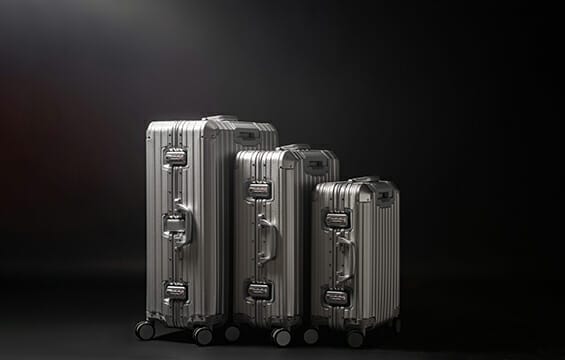 Trois valises argentées à roulettes, parfaites pour les voyages en Europe, sur fond noir.