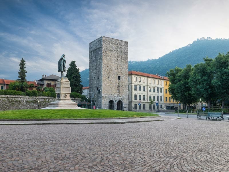 A square with a statue in the middle of it, one of the things to do in Como Italy.