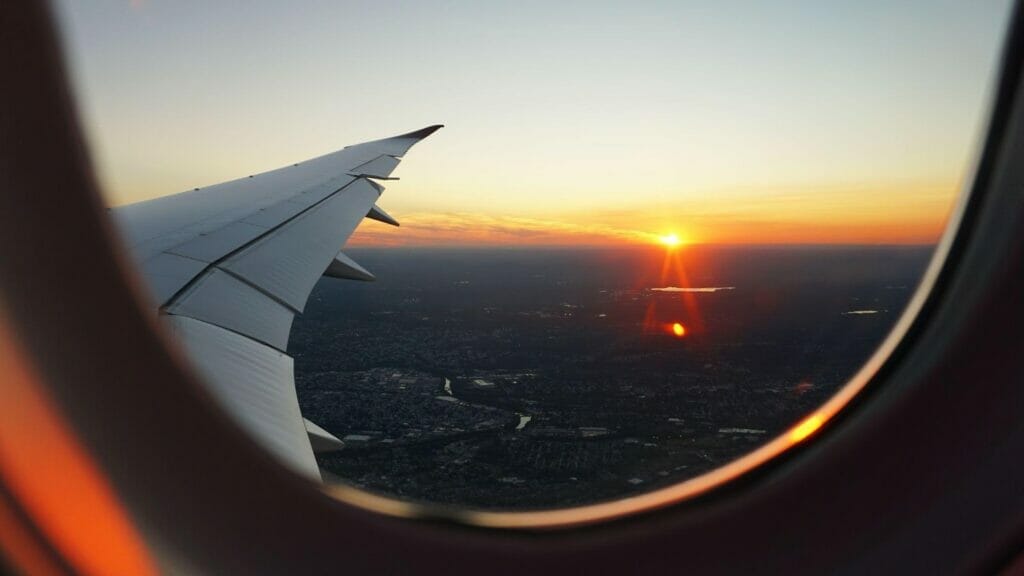 An airplane wing is seen through a window on a flight from Perth to Rome at sunset.