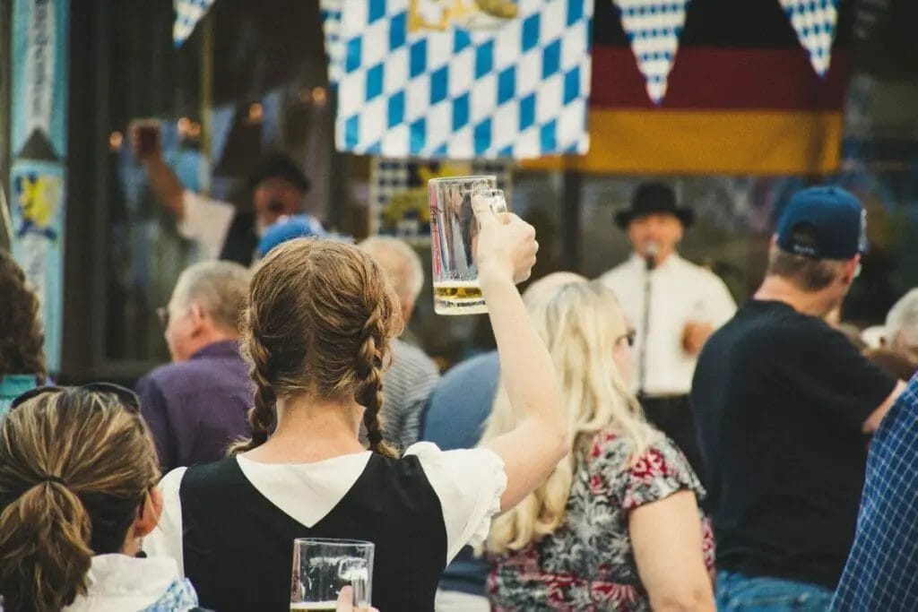 A group of people drinking beer at a festival. - Oktoberfest Travel Guide