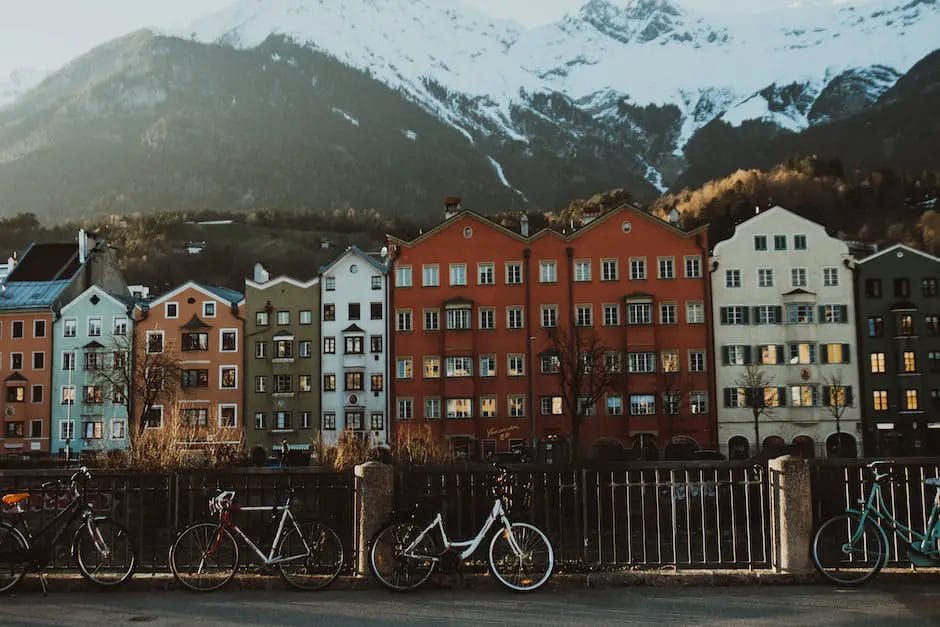 Bicicletas estacionadas frente a edificios con montañas al fondo.