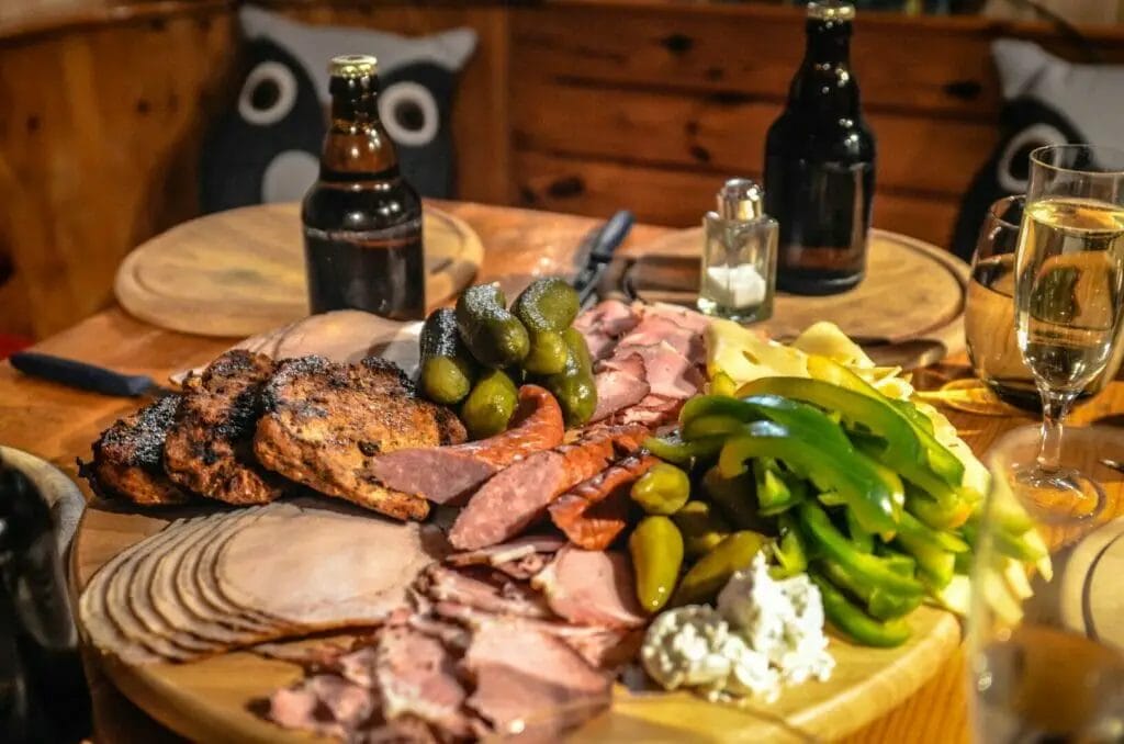 A platter of meat and beer on a wooden table.