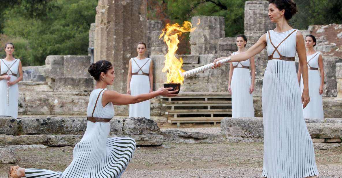 A group of women holding a torch in front of ruins.
