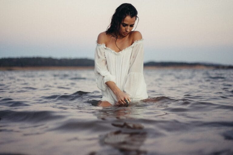 Una mujer con un vestido blanco disfrutando de la serenidad de un cuerpo de agua en España.