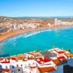 A picturesque view of a breathtaking beach in Europe, with a vibrant cityscape as its backdrop. This destination offers one of the best beach getaways in Europe.