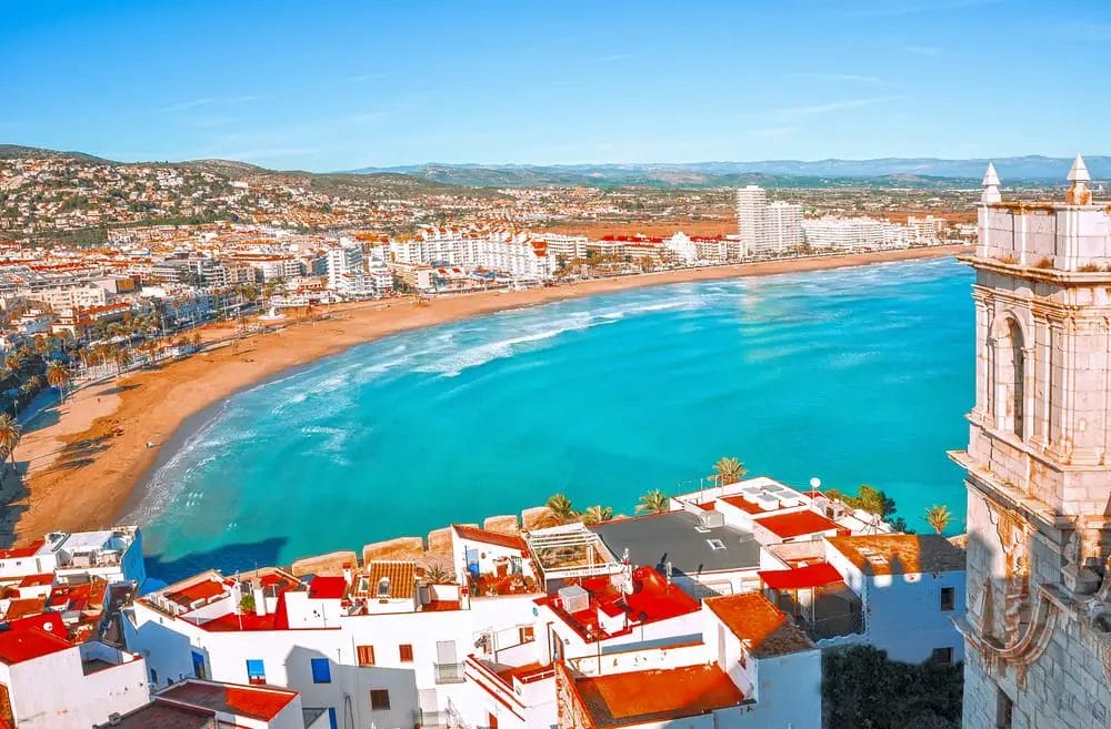 A picturesque view of a breathtaking beach in Europe, with a vibrant cityscape as its backdrop. This destination offers one of the best beach getaways in Europe.