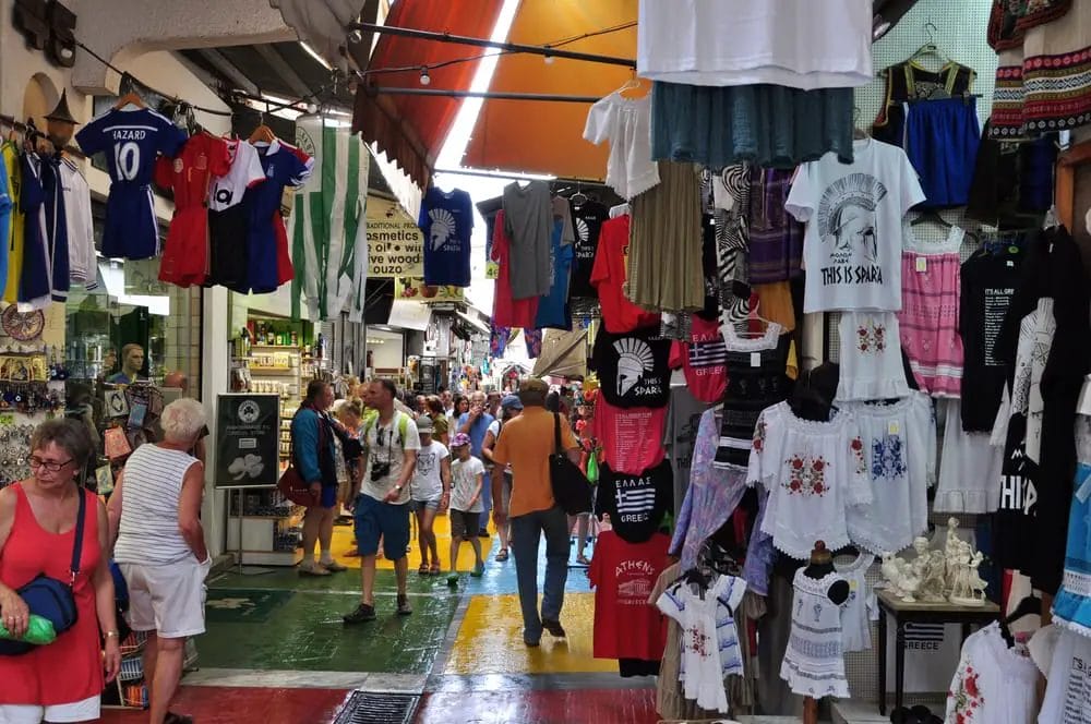 A market with a lot of t - shirts hanging from the ceiling.