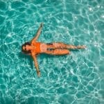 A woman in an orange bikini floating in the water.