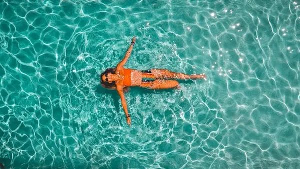 Una mujer en bikini naranja flotando en el agua.
