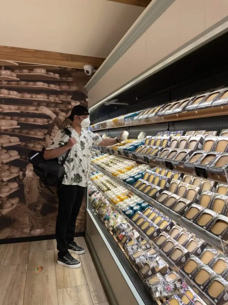 A man is standing in front of a display of pastries in Amsterdam.
