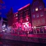 During 2 Days in Amsterdam, experience the enchantment of a canal as it comes alive at night with vibrant red lights.
