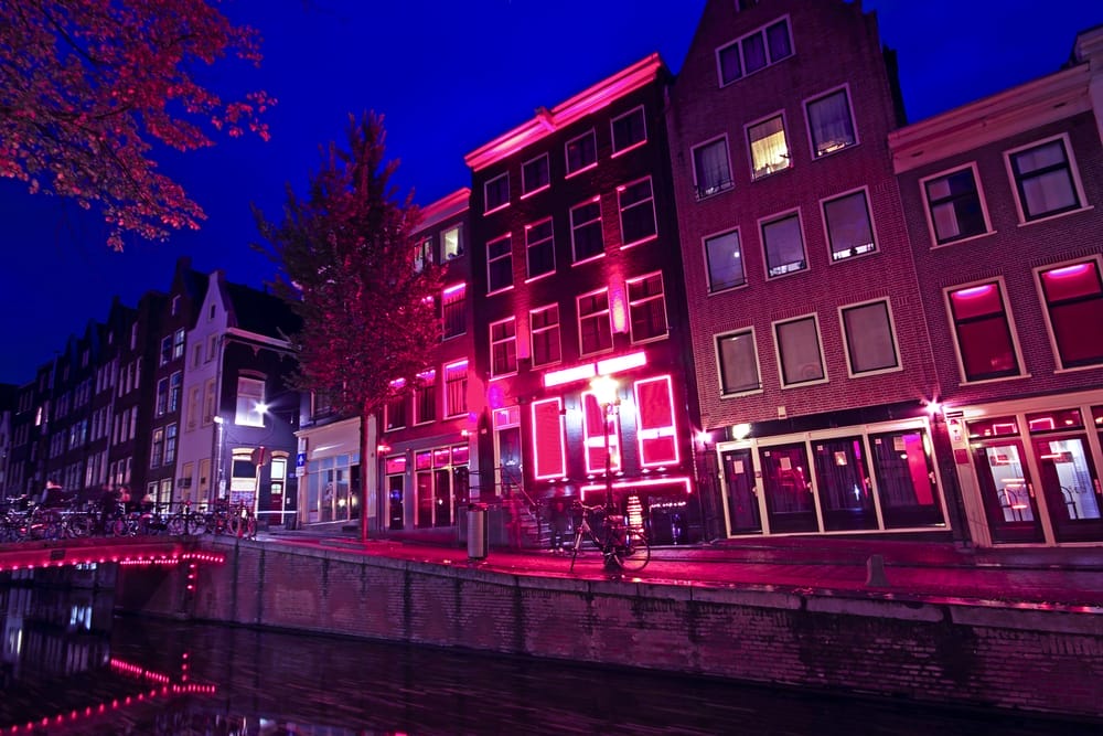 During 2 Days in Amsterdam, experience the enchantment of a canal as it comes alive at night with vibrant red lights.