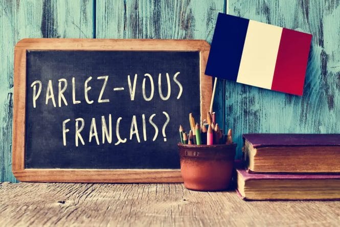 A chalkboard with a french flag and books next to it displaying "Good Morning in French".