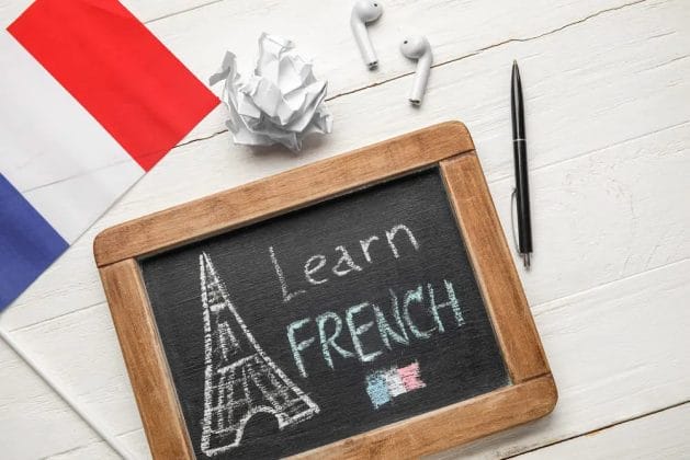 A chalkboard with a picture of a tower and a pen and headphones, displaying "Good Morning" in French.