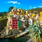 Ecotourism in Italy with colorful houses on a cliff overlooking the ocean.