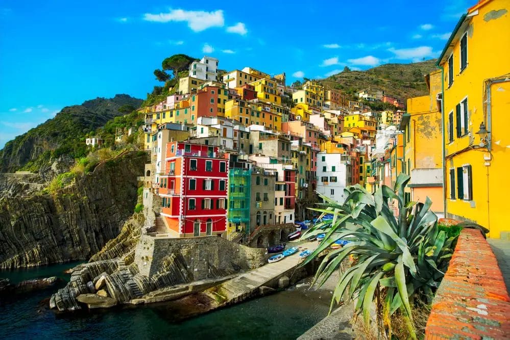Ecotourism in Italy with colorful houses on a cliff overlooking the ocean.