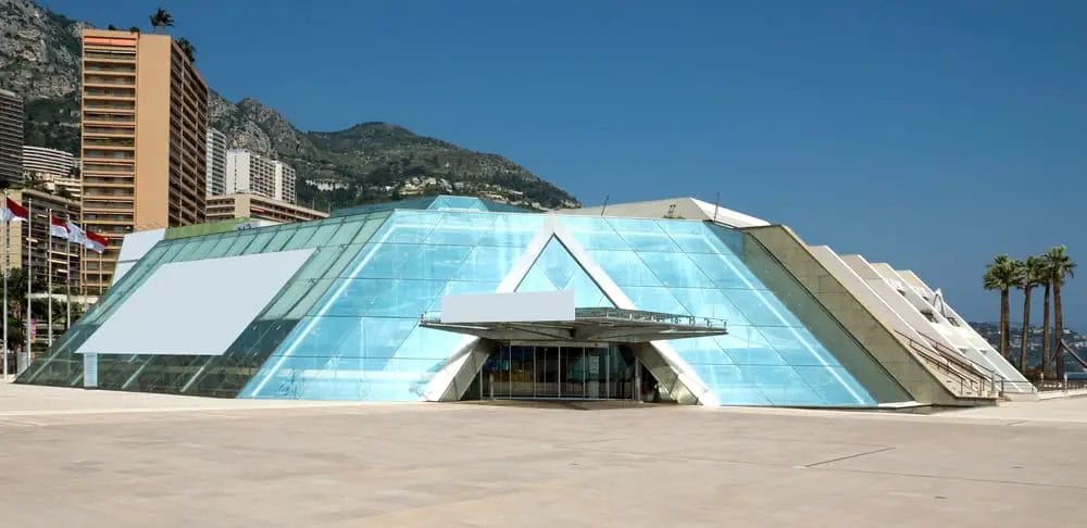 A building with a glass facade and mountains in the background.