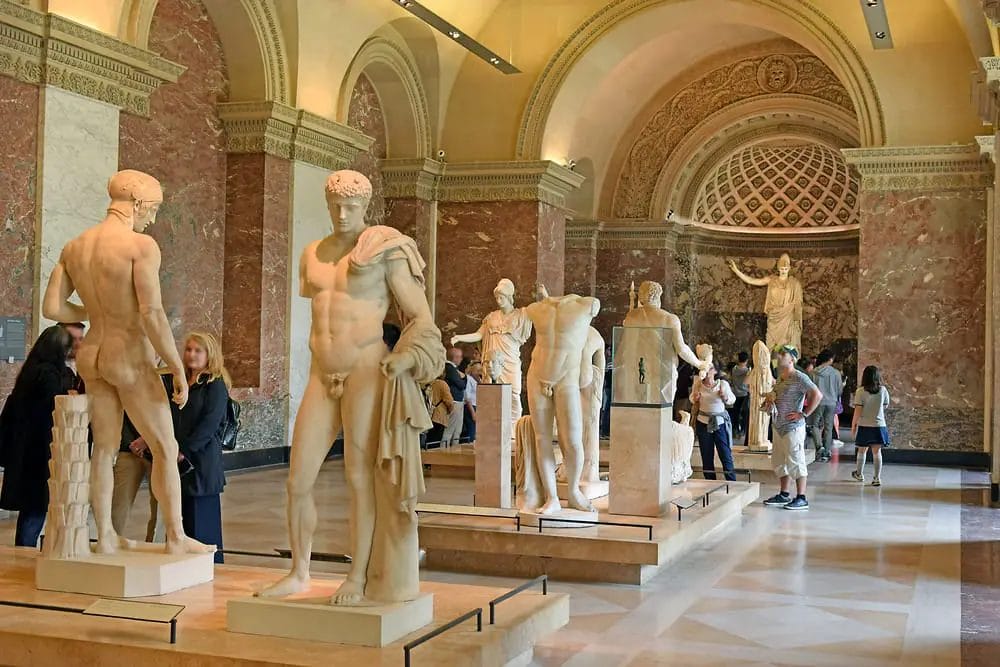 A group of people looking at statues in a museum.