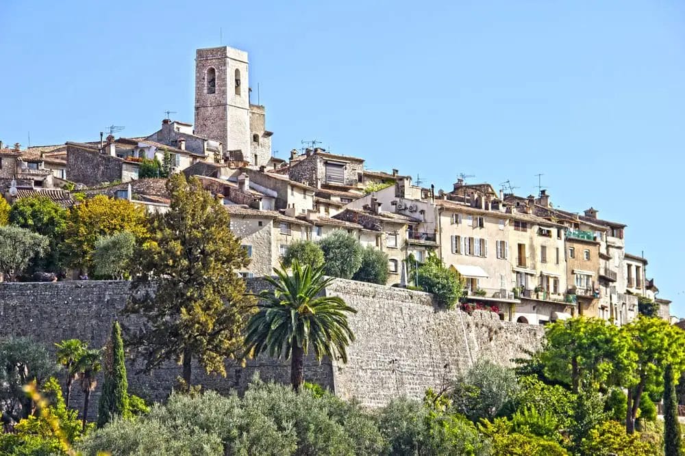 A charming town nestled among rolling hills, complete with a picturesque clock tower at its peak. Perfect for day trips from Nice, France.