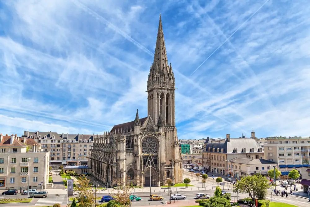 Eine Kirche mit einem Turm mitten in einer Stadt, die zu den Sehenswürdigkeiten der Normandie gehört.