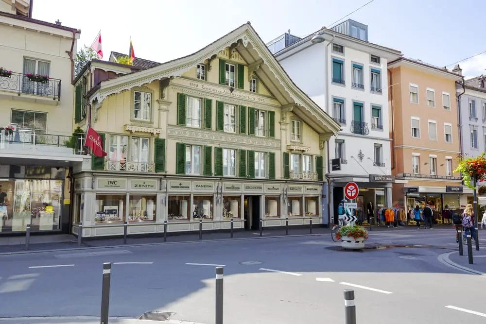 Angolo di una strada europea con un edificio tradizionale che ospita negozi e un cartello di divieto di accesso visibile.