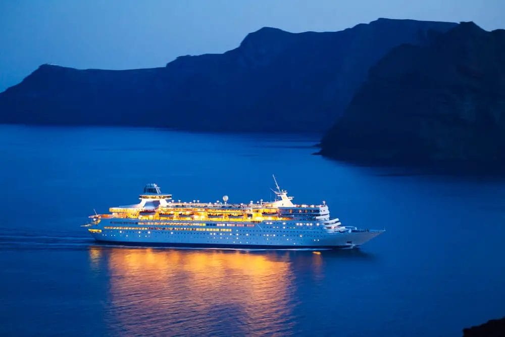 A cruise ship is sailing in the ocean at night.